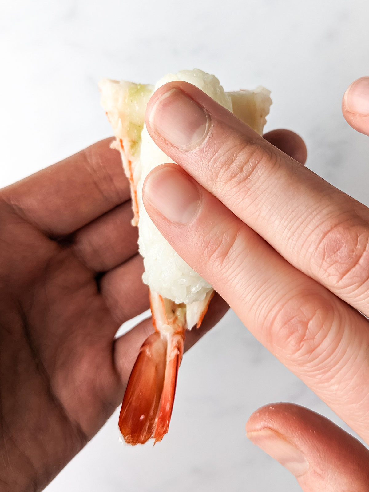 Positioning and pressing down the prepared rice ball onto the shrimp.