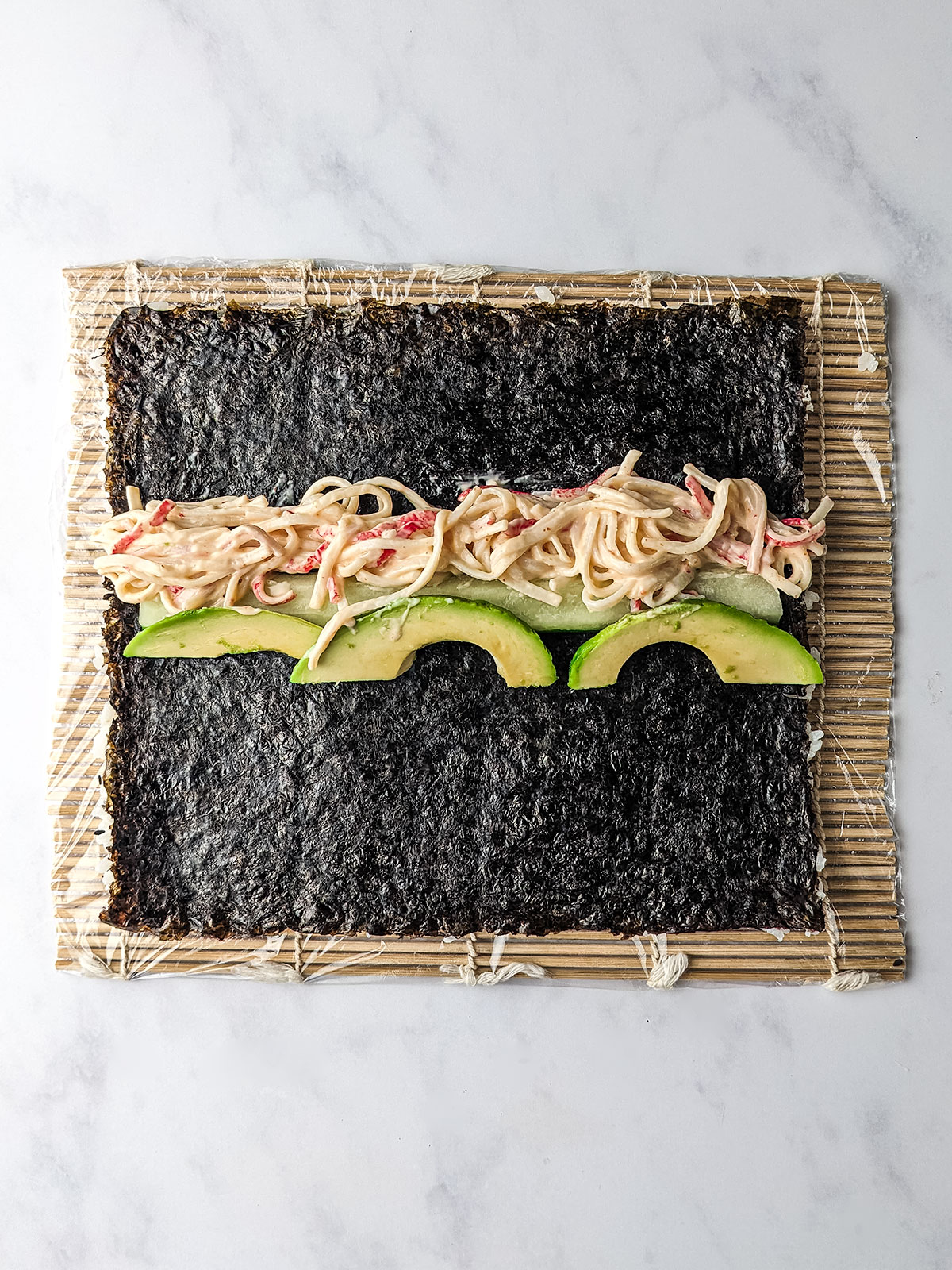 The other side of the nori with the shredded crab, sliced cucumber, and avocado placed in the center.