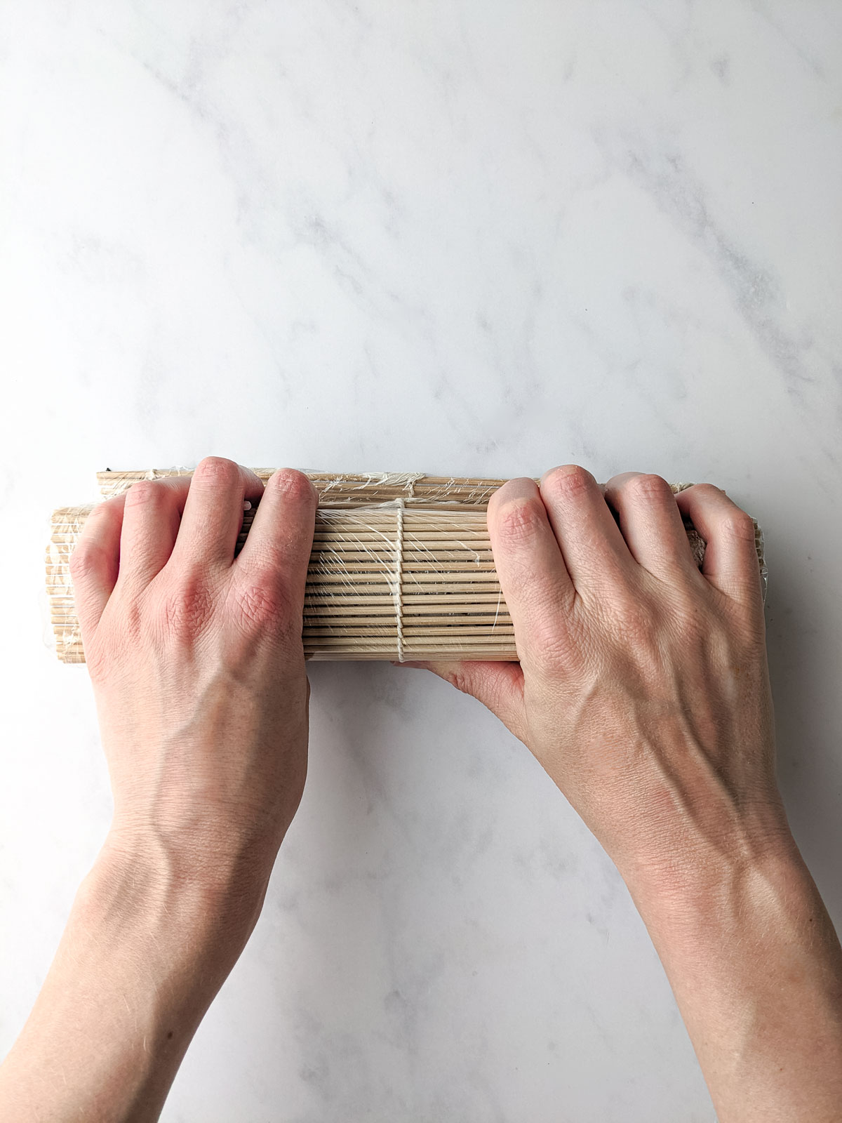 Rolling the bamboo mat to seal and shape the roll.