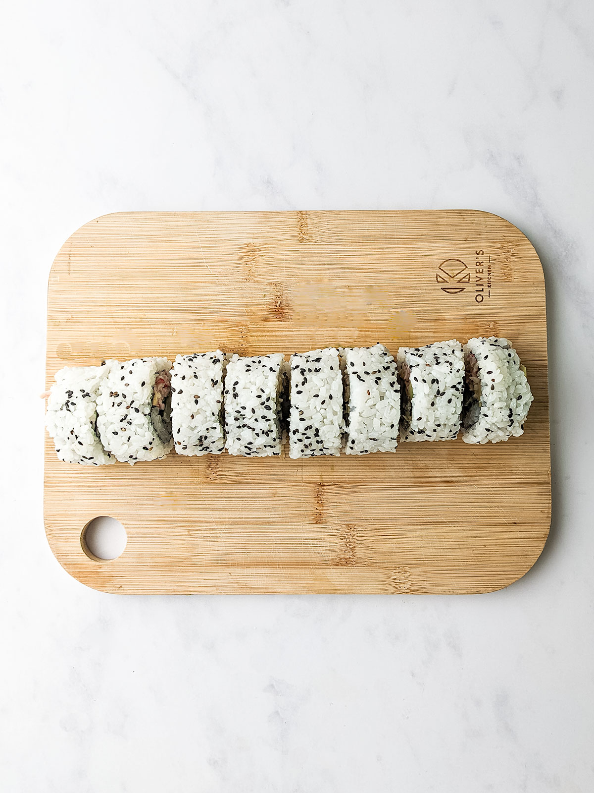 The 8 completed Kani Rolls on a wooden board on a white baclground.