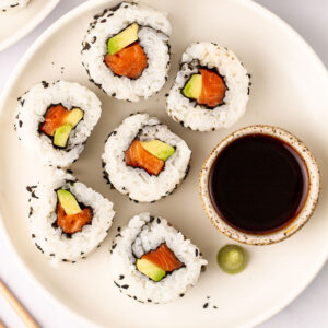 Salmon rolls on a plate with soy sauce.