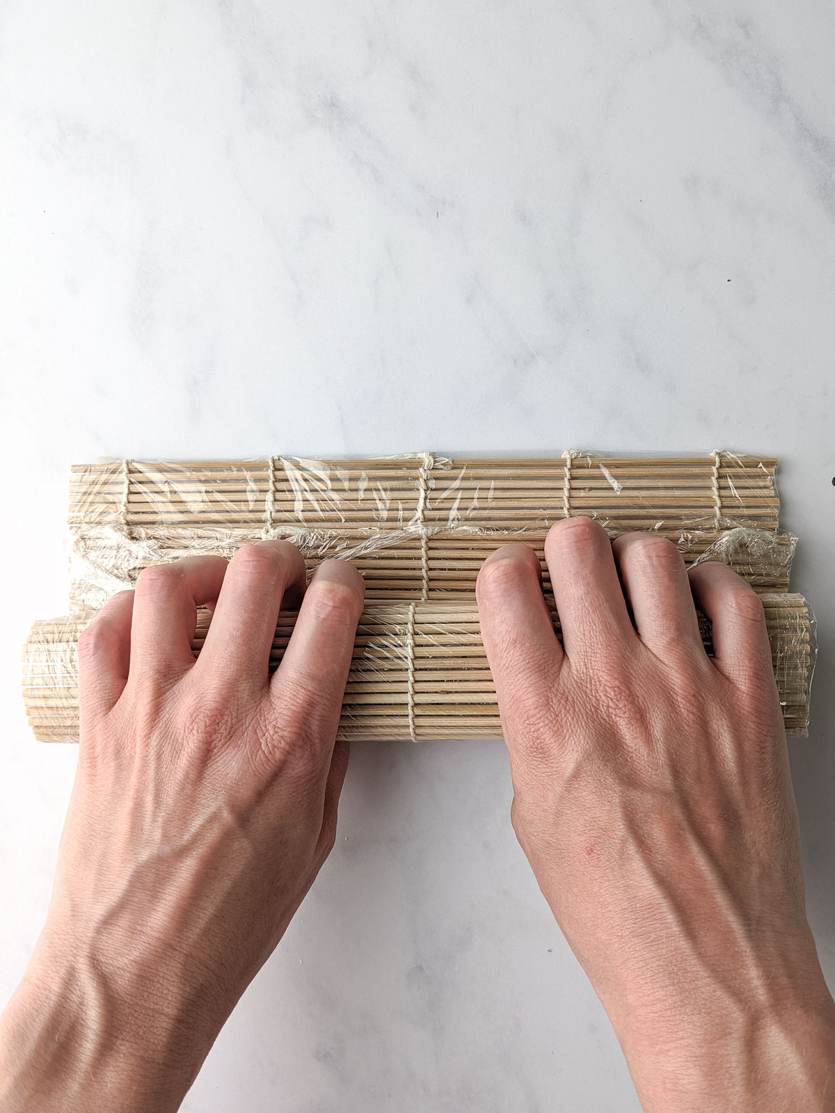 Hands gripping a bamboo rolling mat.